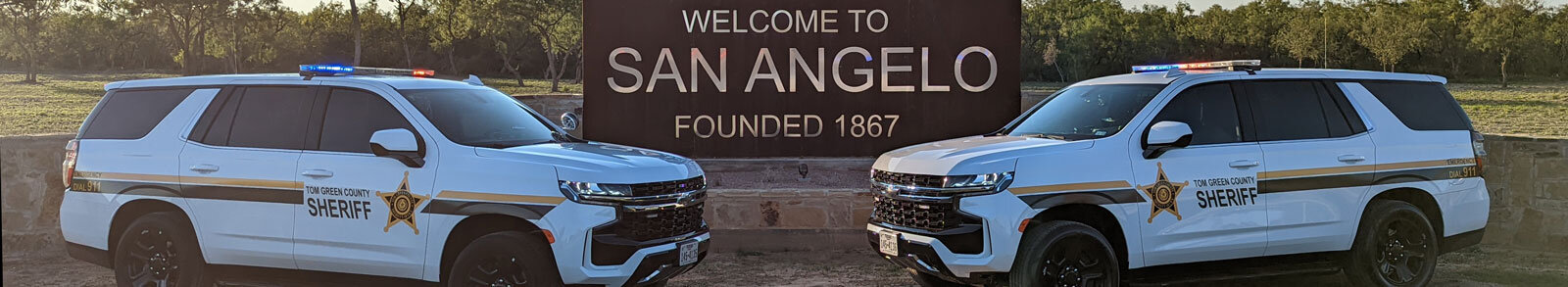 Welcome to San Angelo sign with 2 Tom Green Sheriff Vehicles parked in front